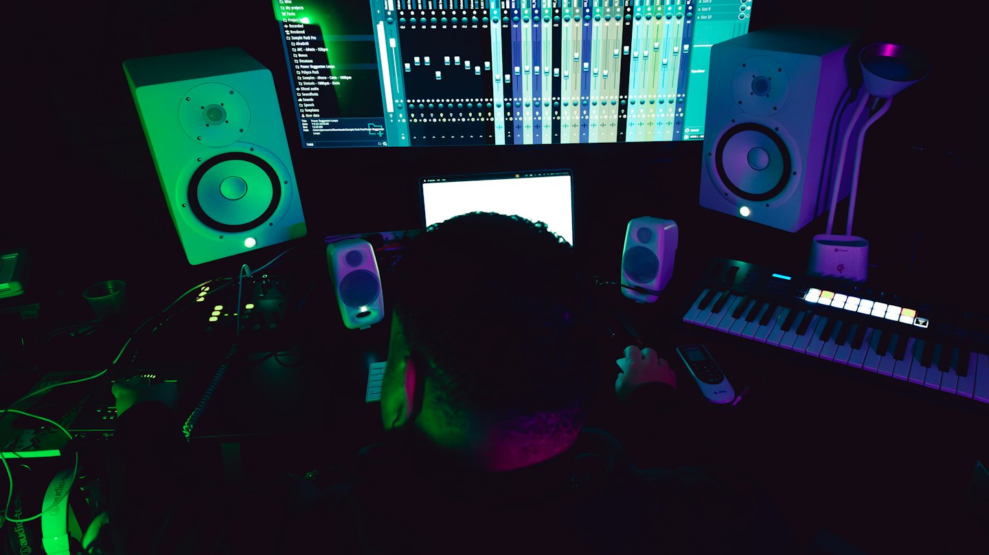 Music producer working at a workstation with multiple computer screens.